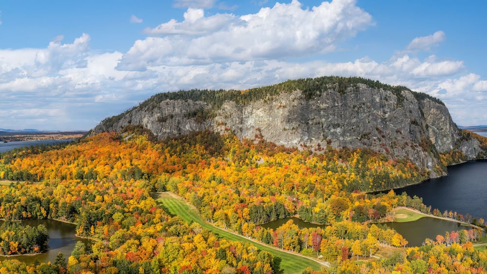 A rocky island surrounded by a lake with autumn foliage.