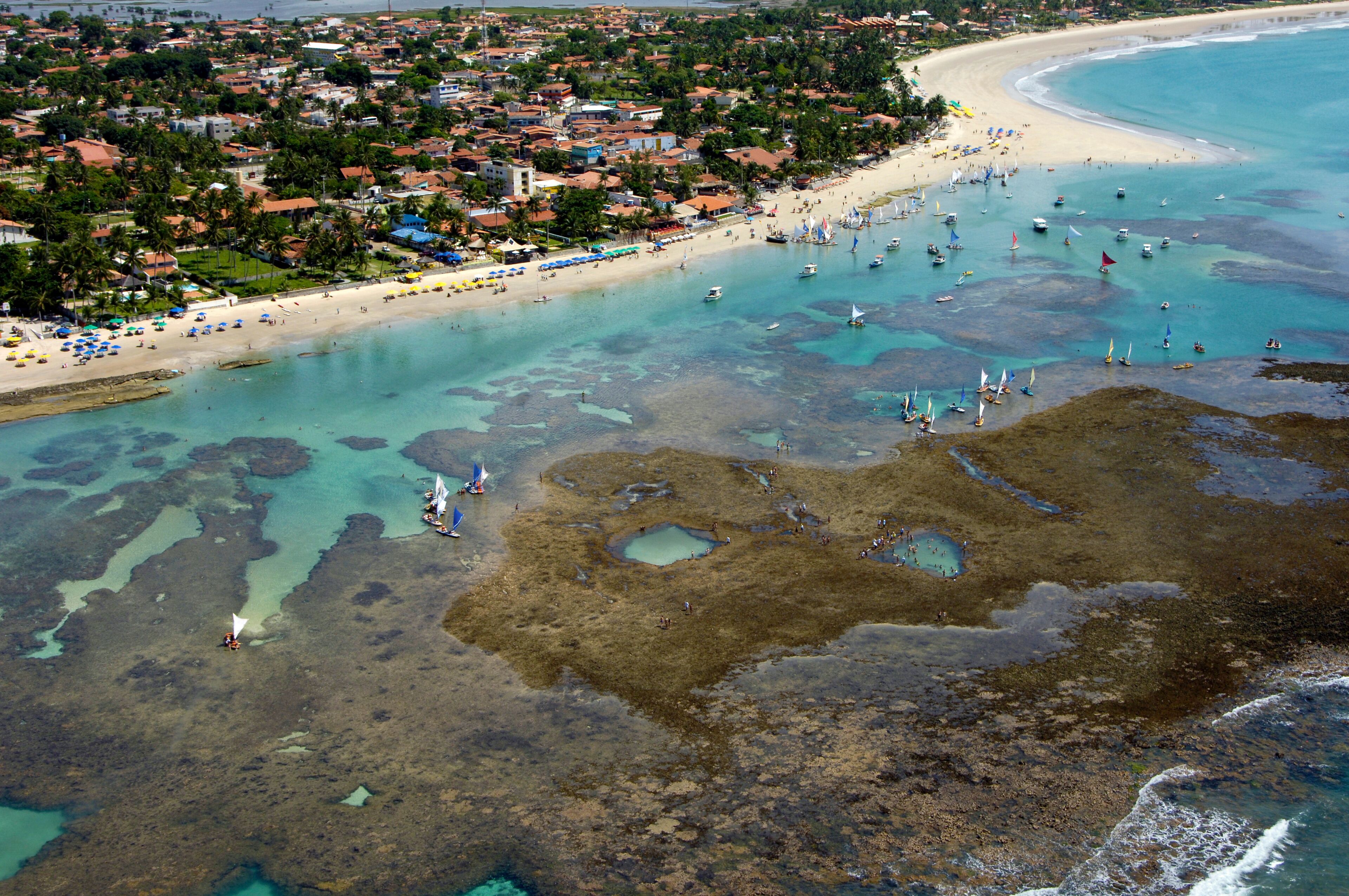 A coastal town with a beach, clear waters, and boats.