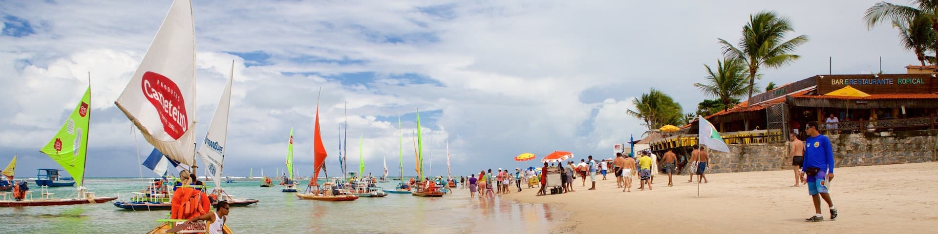 A beach with sailboats, people, and a restaurant.