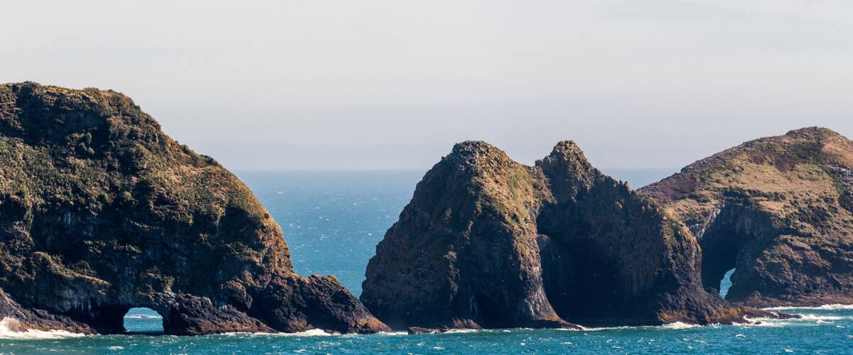 A coastal landscape with prominent rock formations and a sea arch.