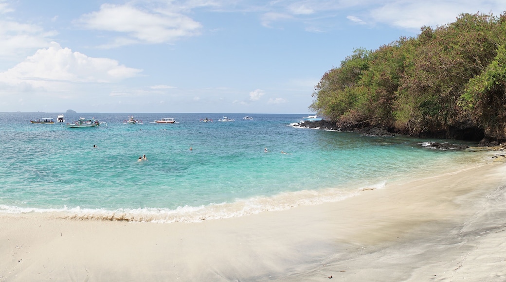 Boats and people visiting Tropical Blue Lagoon Beach near Bali in Indonesia.