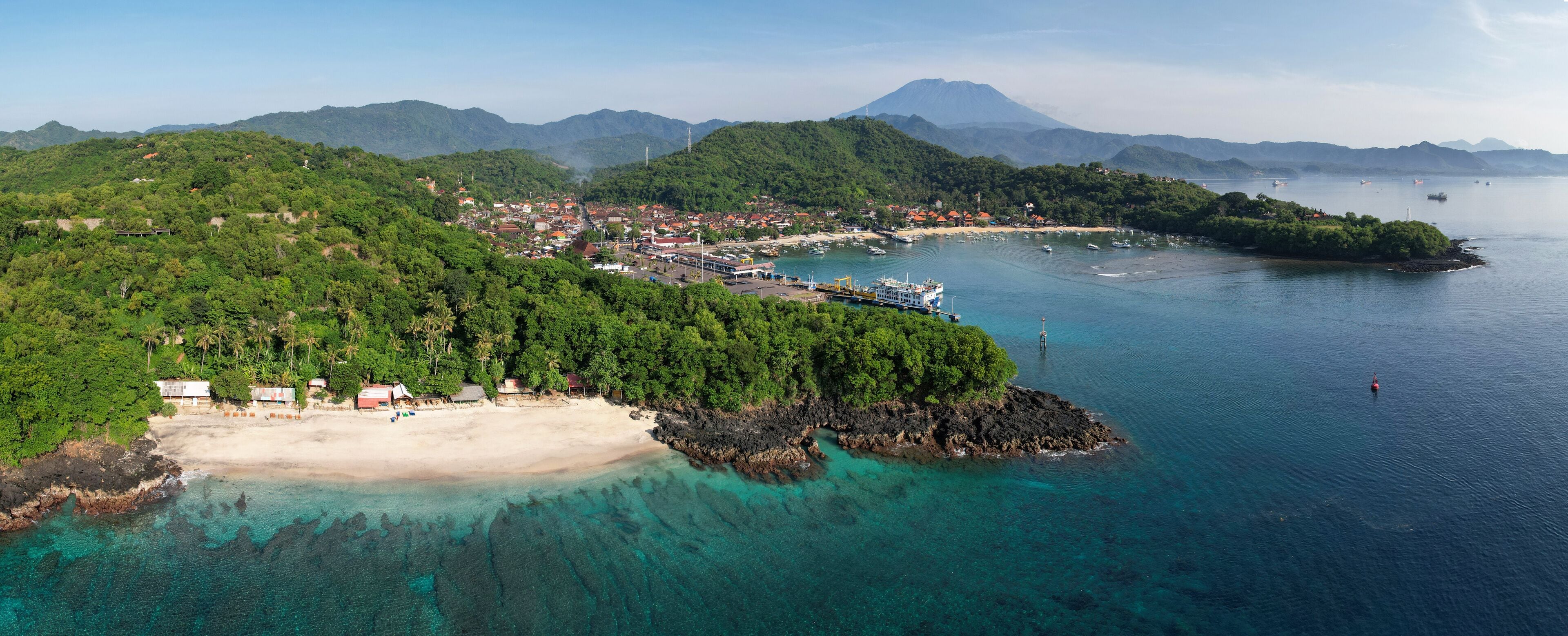 Panoramic aerial view of Bias Tugel Beach, Padangbai bay and Mount Agung on sunny day. Manggis, Bali, Indonesia.