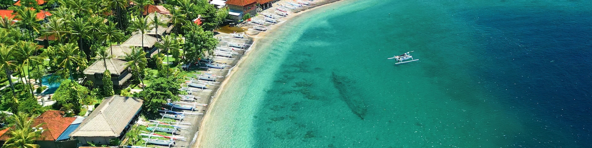 Un pueblo costero con una playa extensa bordeada de barcos y casas.