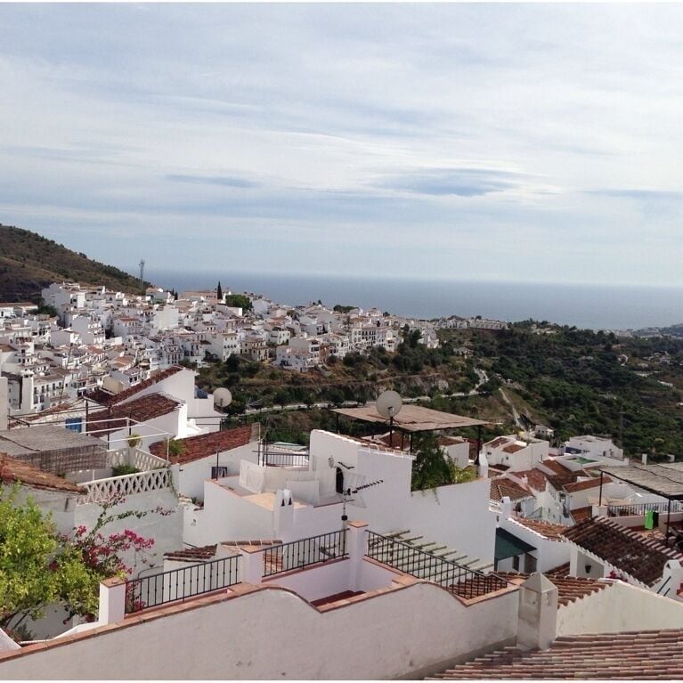 A coastal town with white buildings, terraced roofs, and a view of the sea.