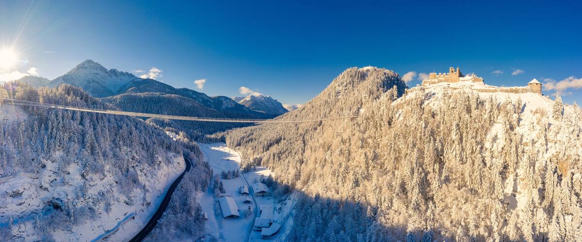 A snow-covered mountain landscape with a bridge and a castle.