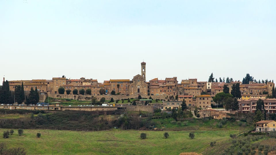 A historic town with a prominent tower, surrounded by traditional buildings and green fields.