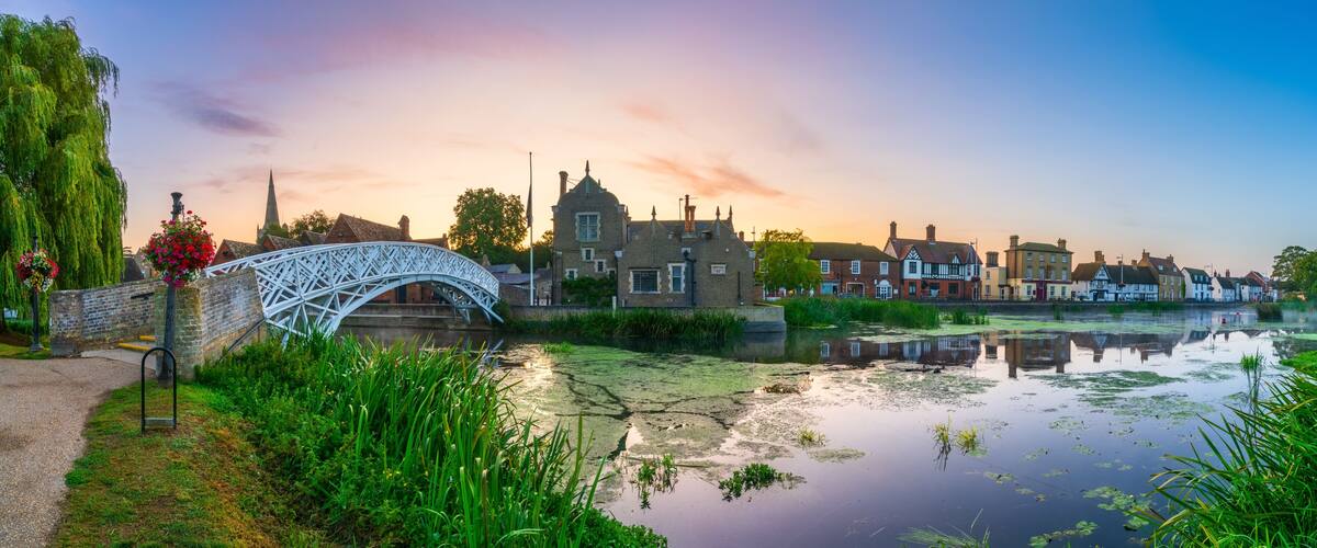 A historic bridge, a river, and traditional buildings during sunset.