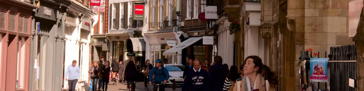 A bustling street with historic buildings, shops, and cyclists.