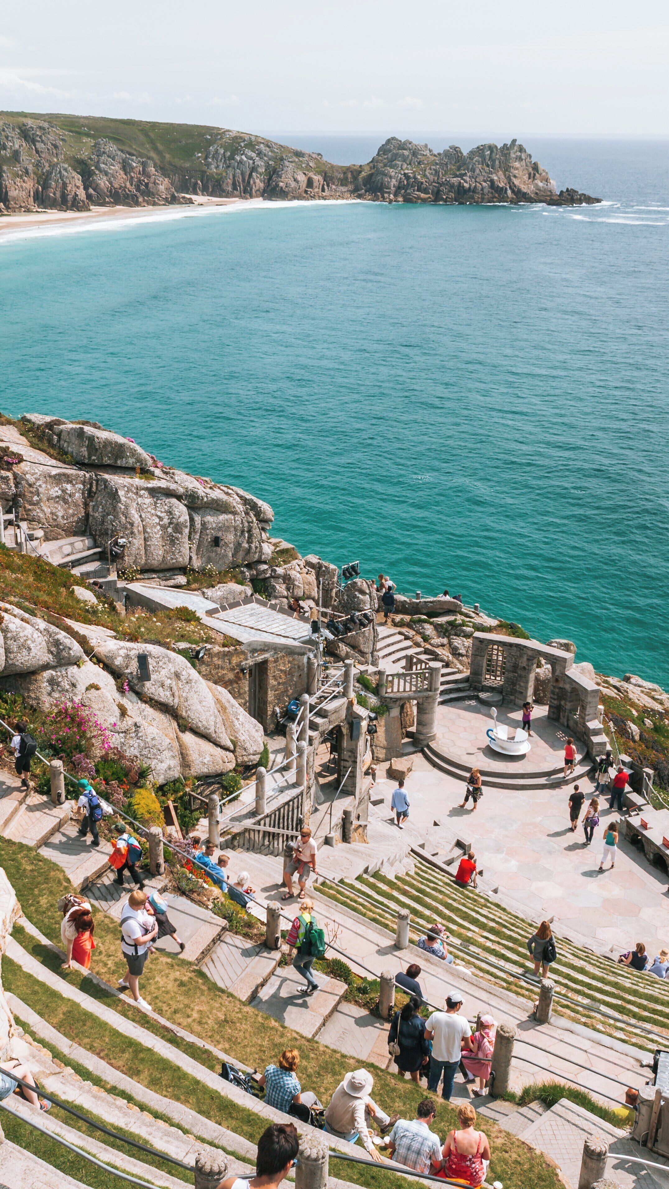 View of Minack Theatre overlooking the stunning coastline of Penzance, England during a lively summer performance with audience enjoying the scenery