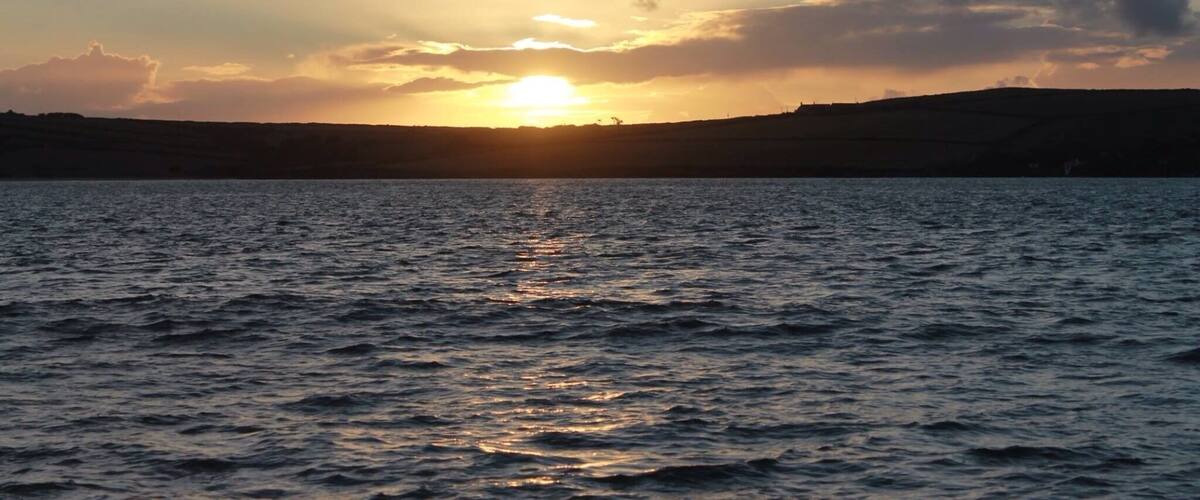A sunset over a body of water with a distant shoreline.