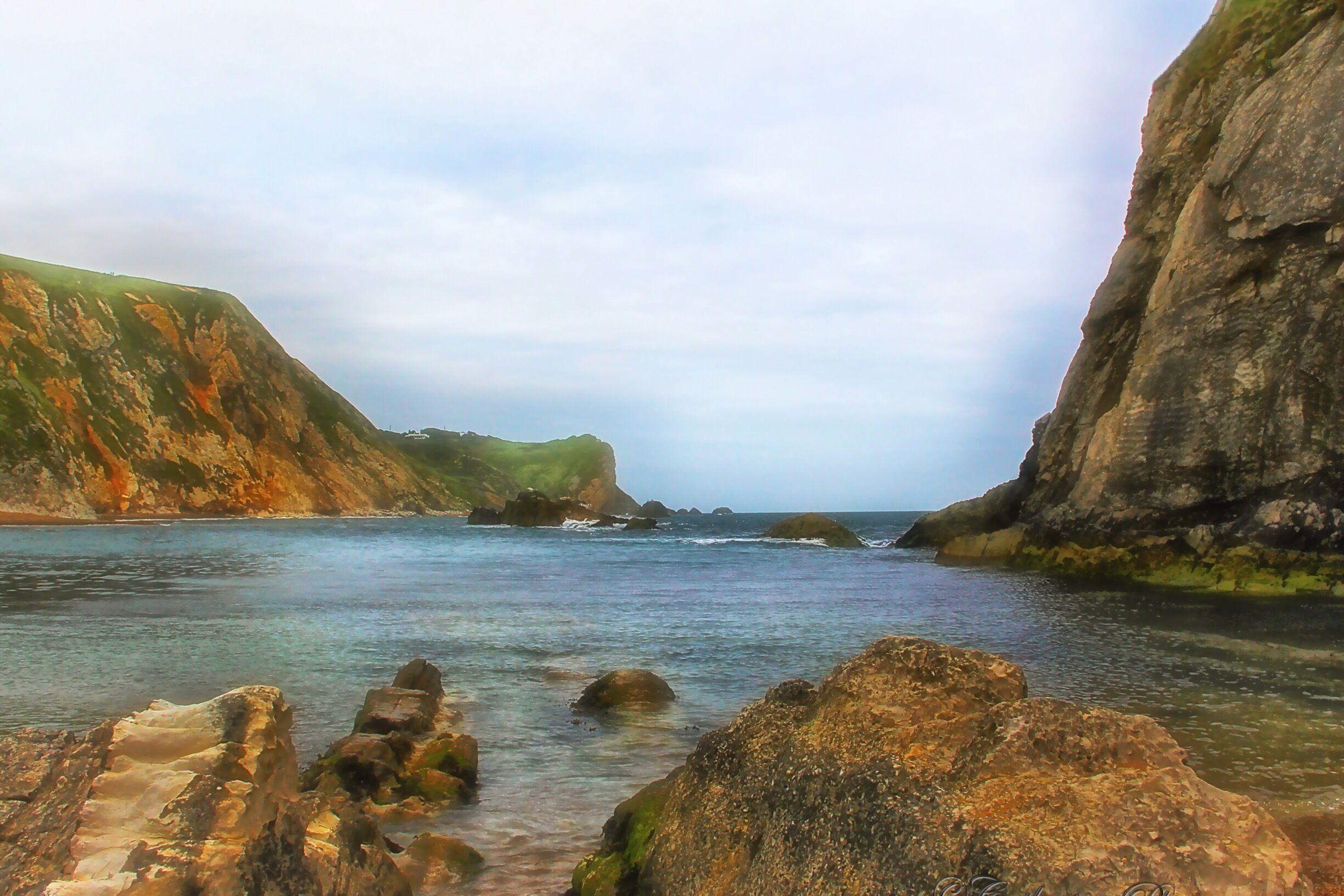 A coastal landscape with rocky cliffs and calm sea.