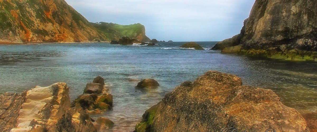 A coastal landscape with rocky cliffs and calm sea.
