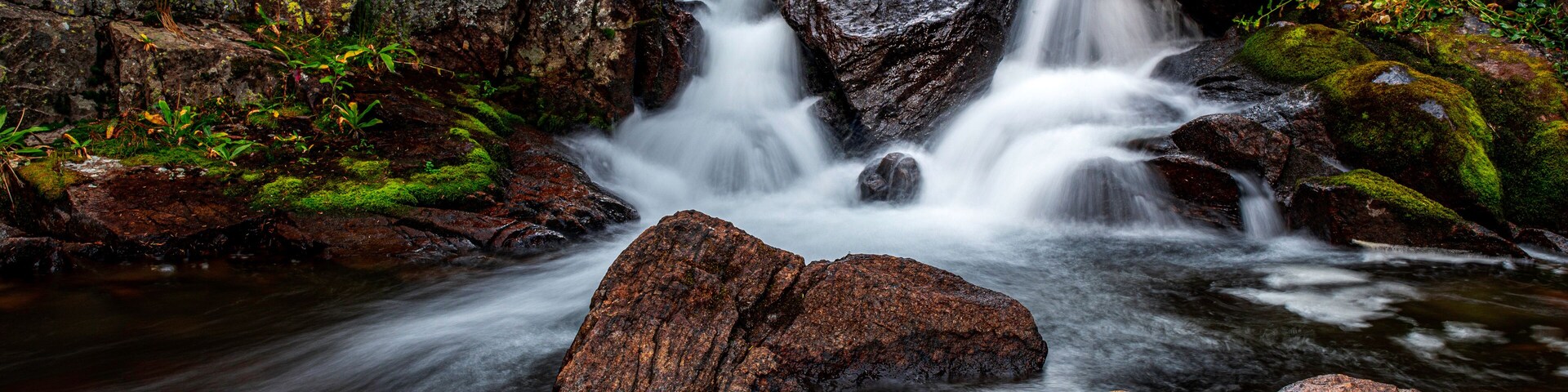 A waterfall cascading over rocks in a forested area.