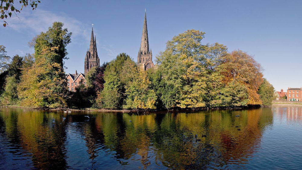 A river reflecting a cathedral and surrounding trees.