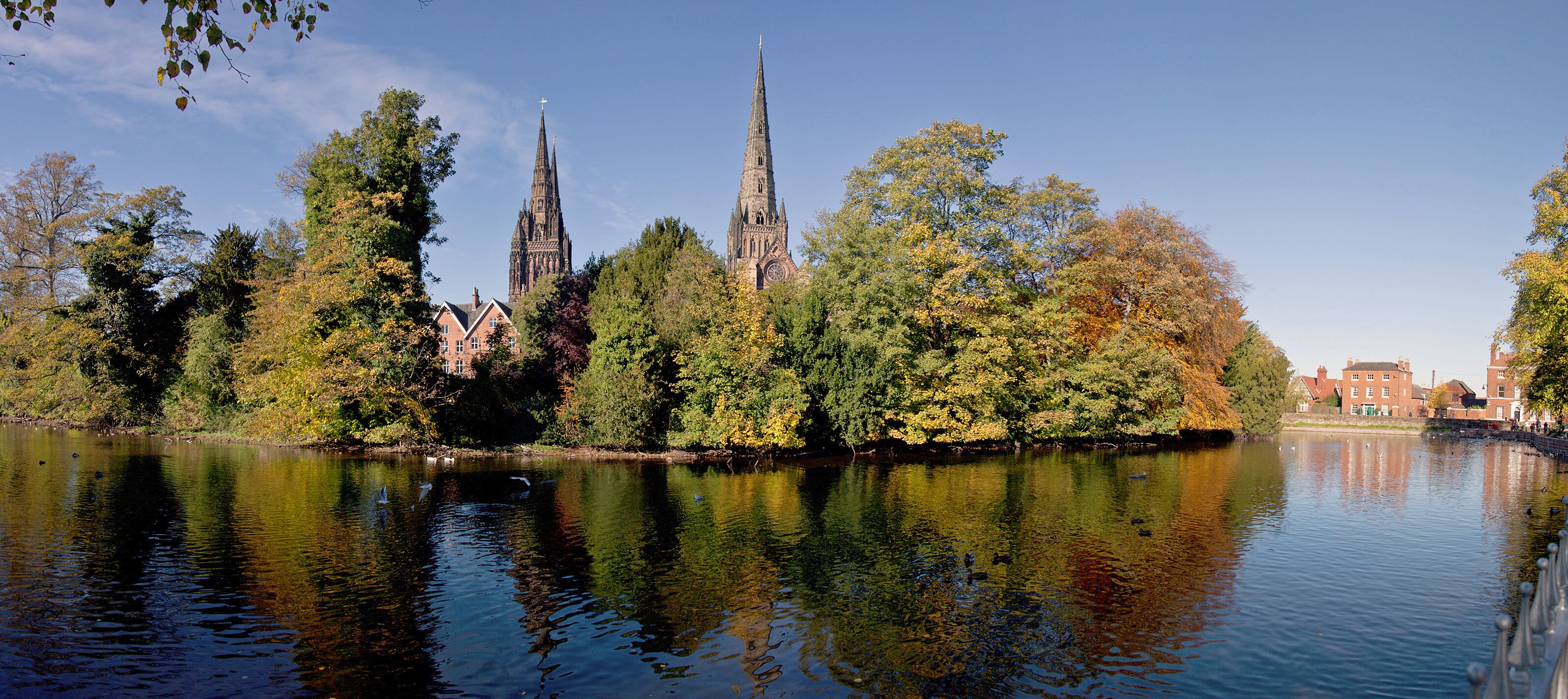 A river reflecting a cathedral and surrounding trees.
