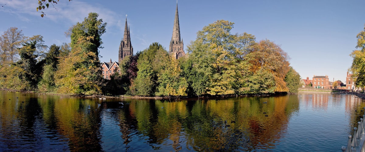 A river reflecting a cathedral and surrounding trees.