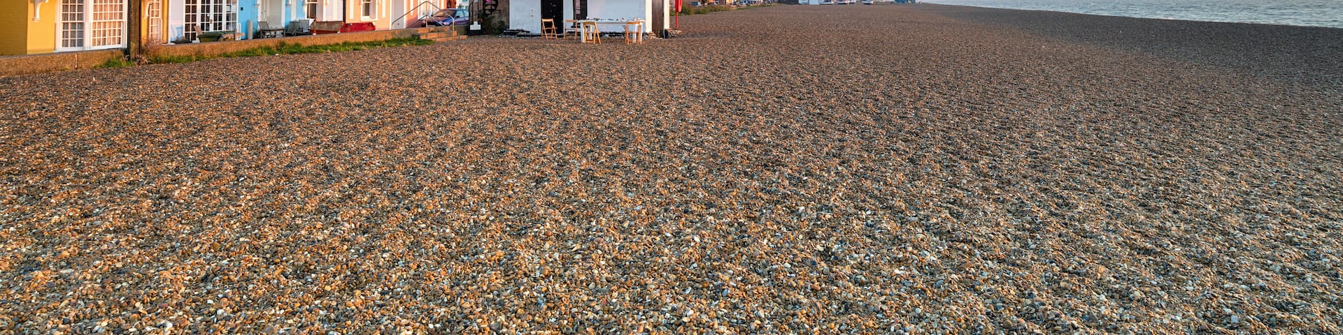 A pebbled beach with colorful houses and a clear sky.
