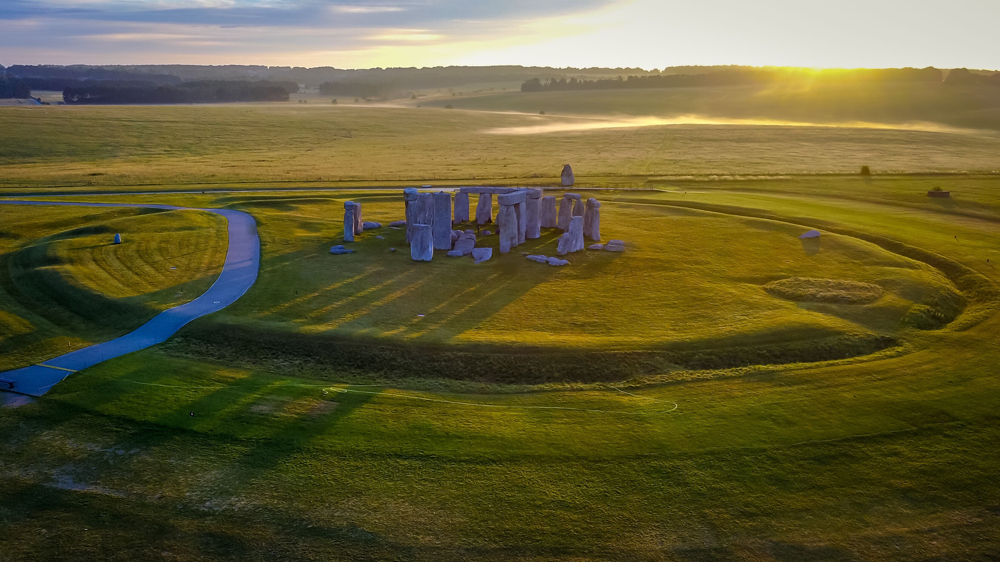 A stone circle with a winding path in a grassy field.