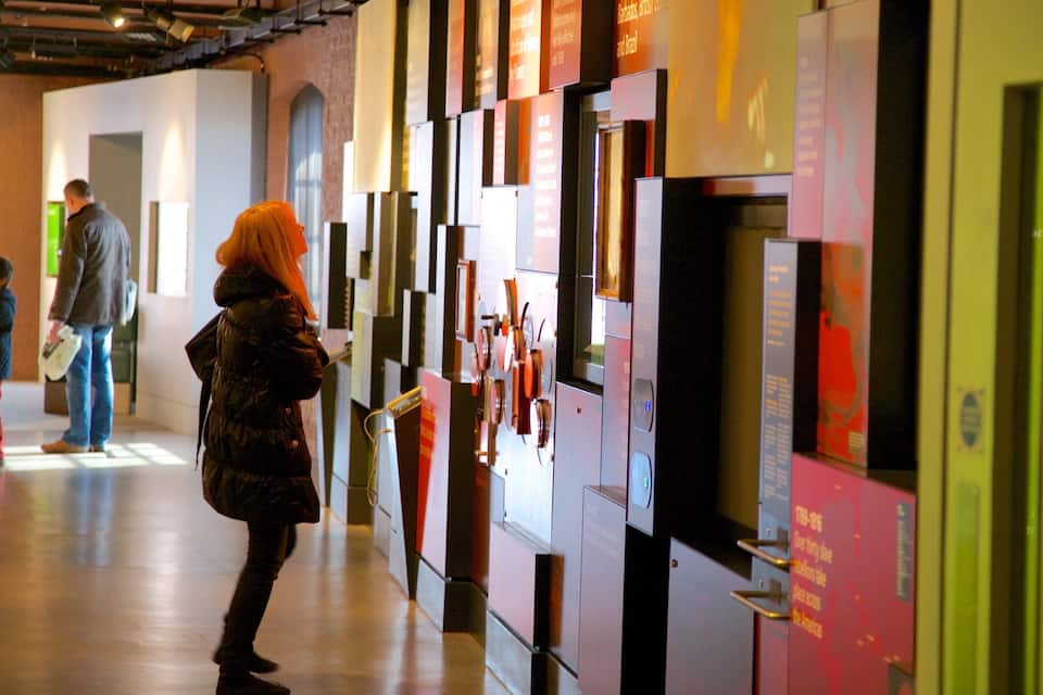 A person examining a wall with various posters and information boards in a hallway.