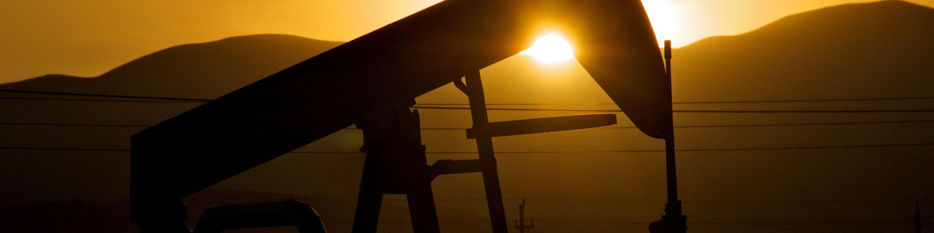 Silhouette of pump jack in setting sun, Taft, California. May be use as Metaphor for “Sun setting on fossil fuels”