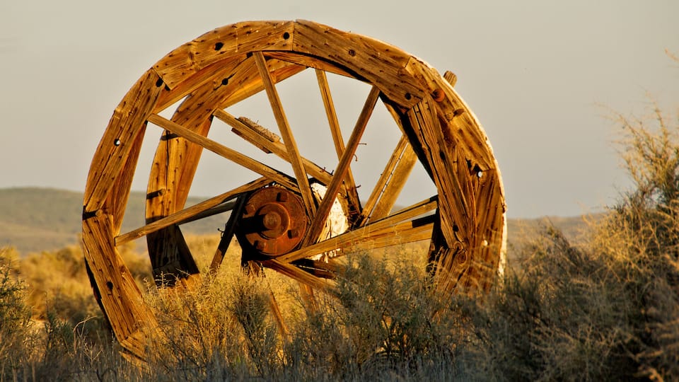 A large wooden wheel in a field.