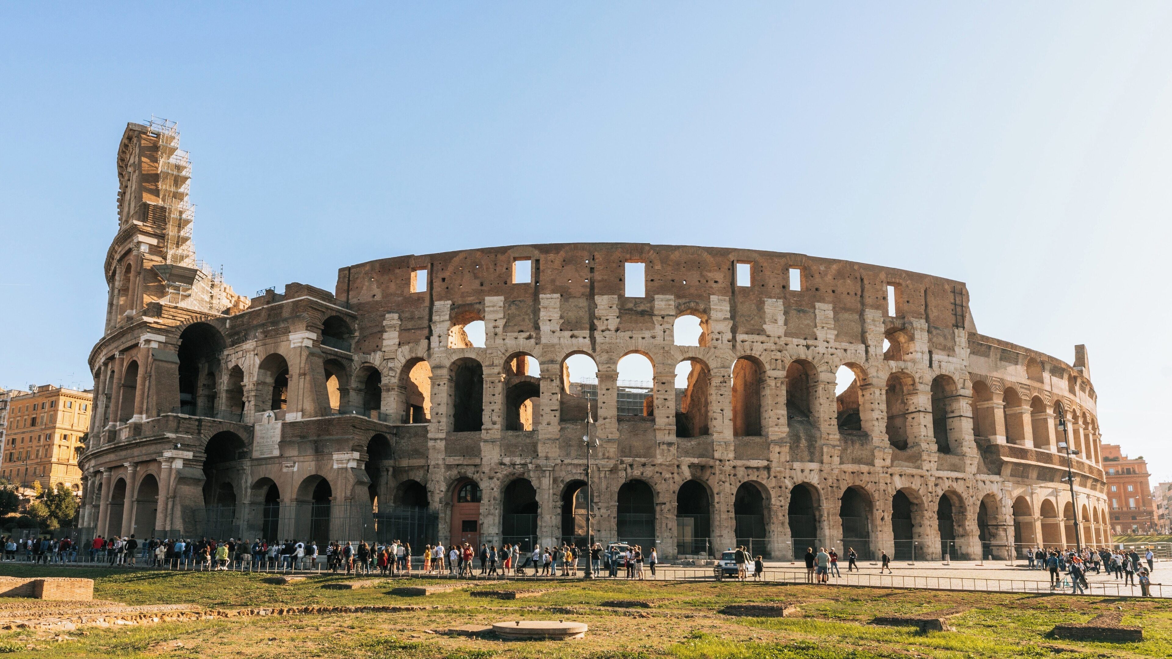 Explore the magnificent Colosseum in Celio, Rome during a sunny day with tourists admiring its ancient architecture and rich history