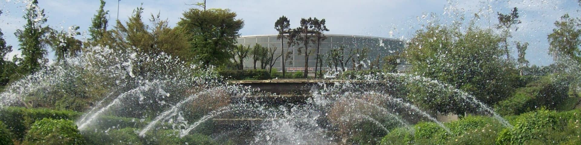 A cascading waterfall with multiple tiers, surrounded by lush greenery and trees.
