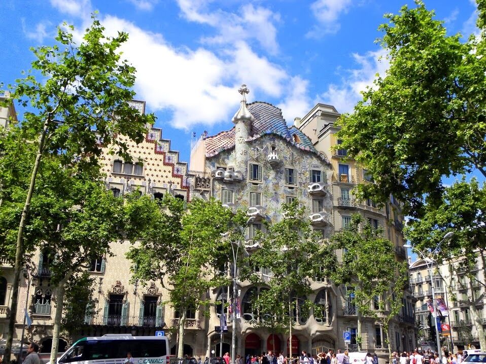 A historic building with unique architecture, surrounded by trees and a clear blue sky.