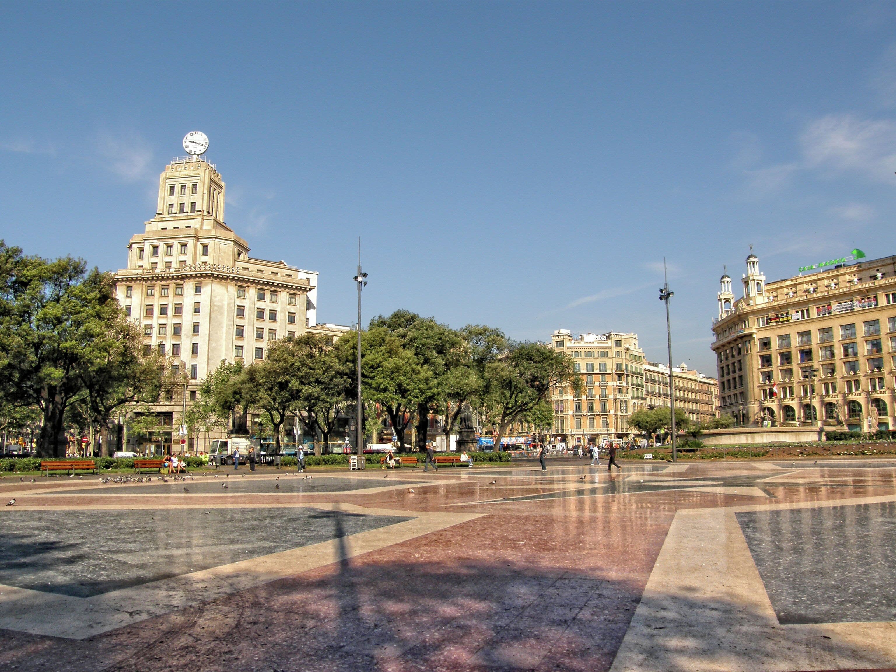 Una plaza con edificios grandes, árboles y cielo despejado.