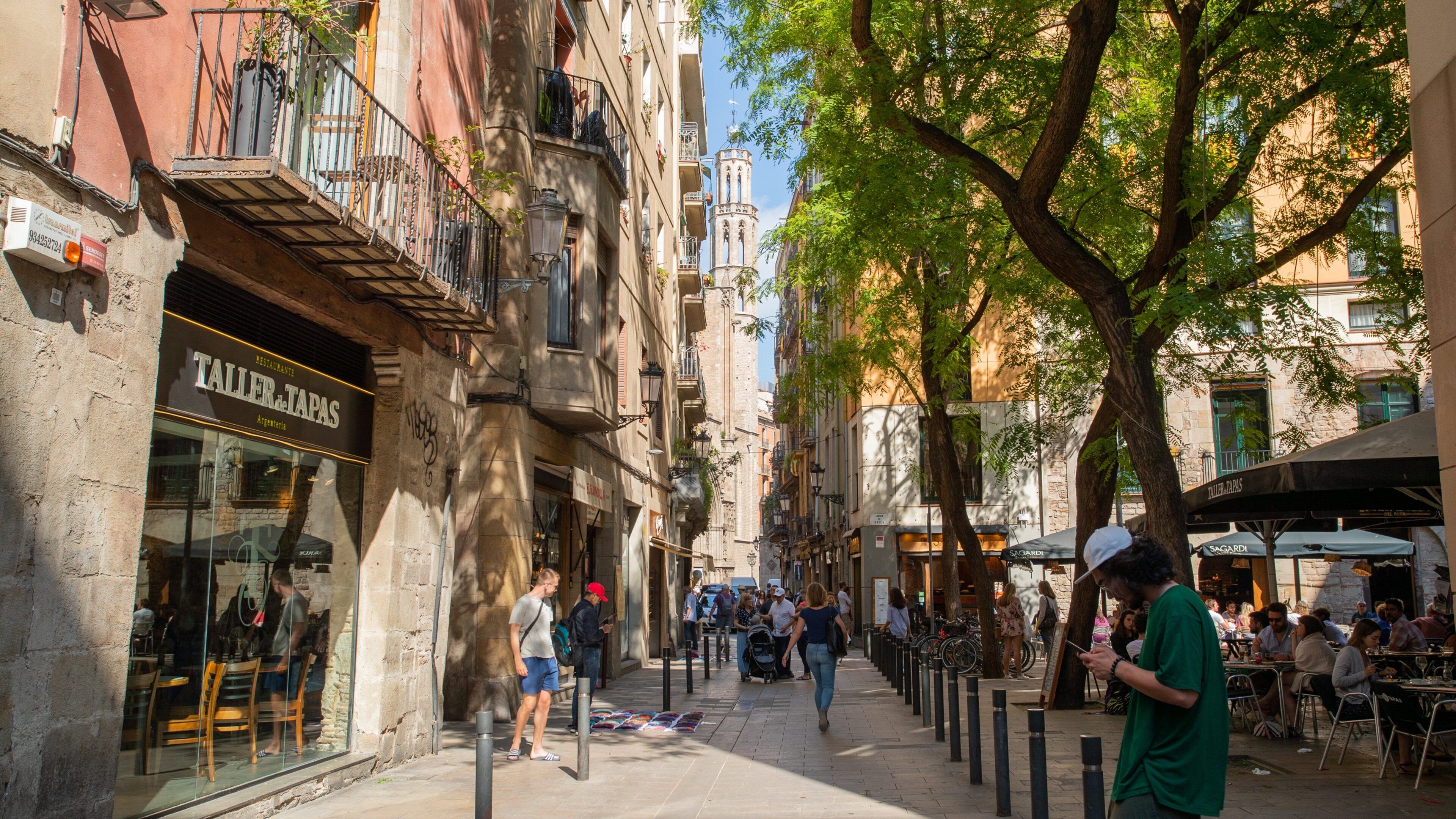 A bustling street lined with cafes and shops, with people walking and sitting outside.
