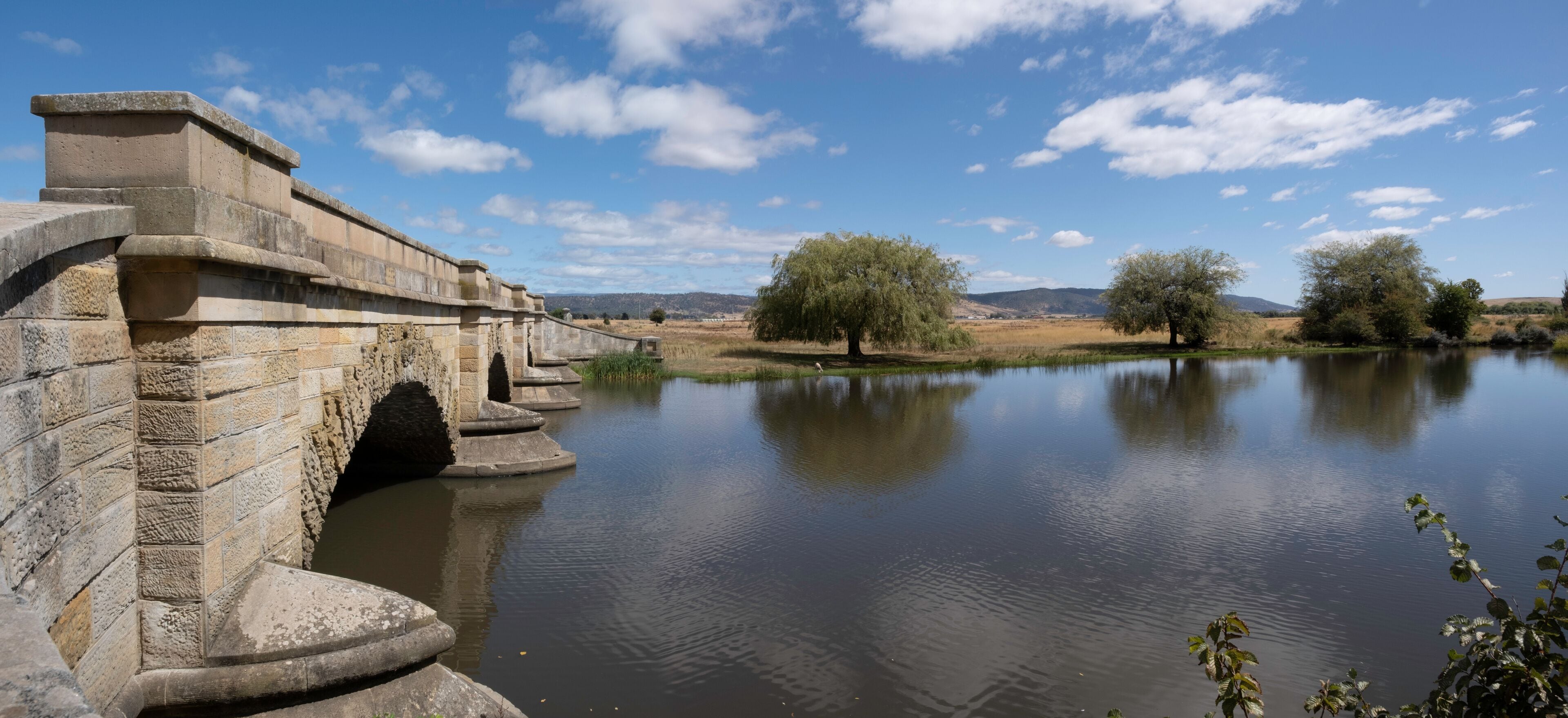 Historic sandstone convict bridge over the Macquarie river in Ross, Tasmania, Australia with beautiful sunny landscape. Widescreen image