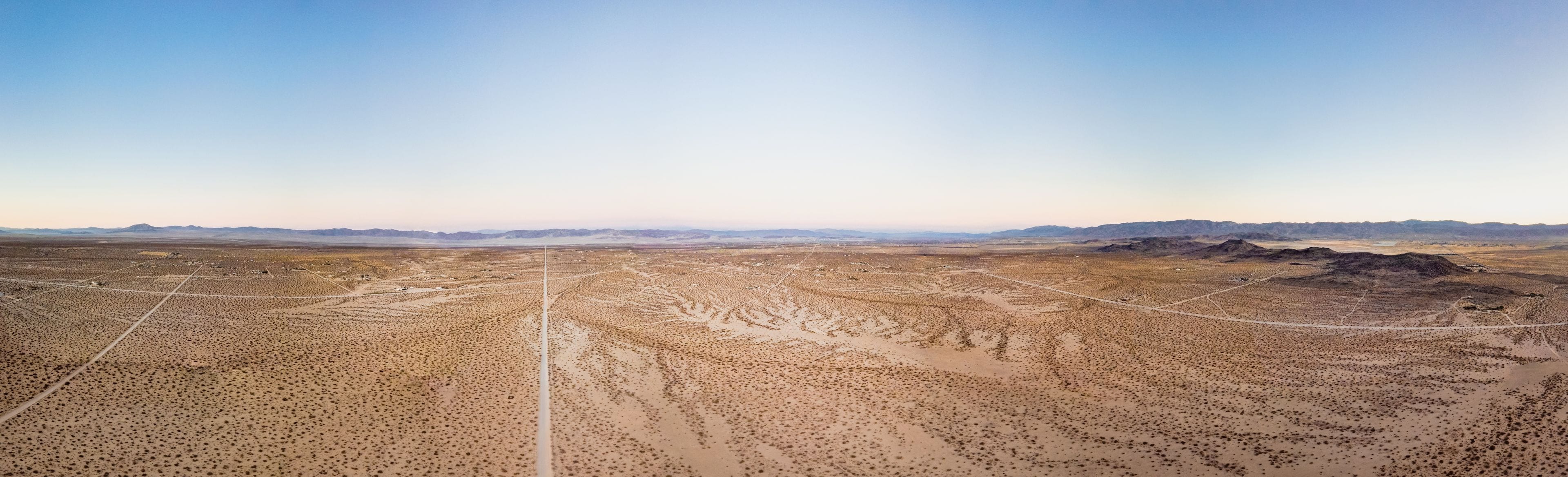 A vast desert landscape with sparse vegetation and a clear sky.