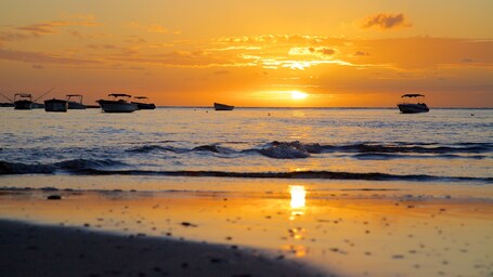 Ein Sonnenuntergang über einem ruhigen Meer mit mehreren ankernden Booten.