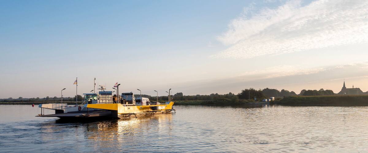 A yellow boat on a calm river with a distant temple and trees.