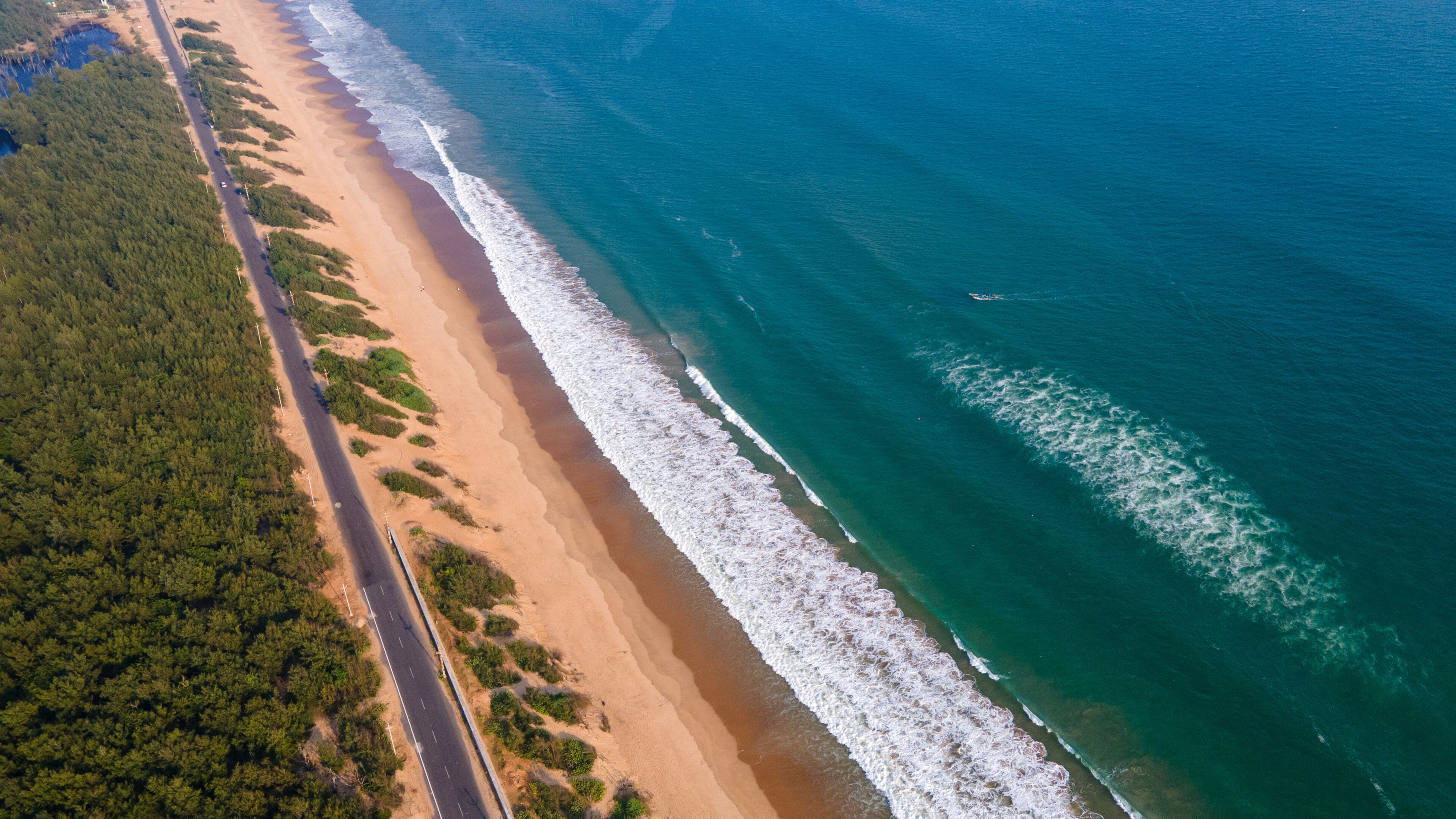 Scenic aerial view of Puri Konark Marine Drive coastline, Odisha, India, with wide sandy beach, turquoise ocean, palm-lined shore, and natural tropical seascape