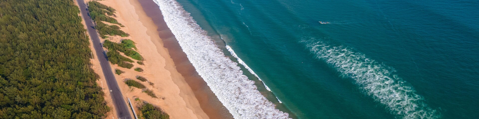 Vista aérea de uma estrada costeira com uma praia e oceano.