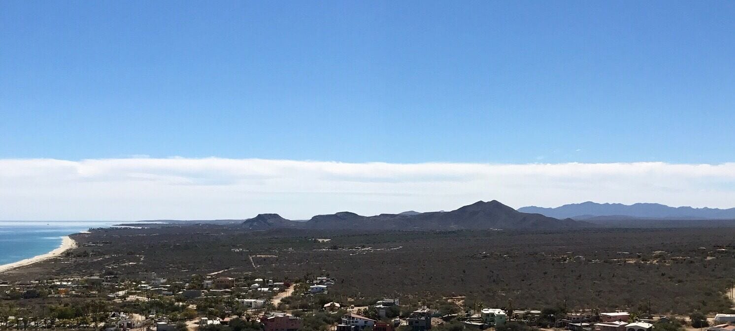 Un pueblo costero con playa, montañas y vegetación escasa.