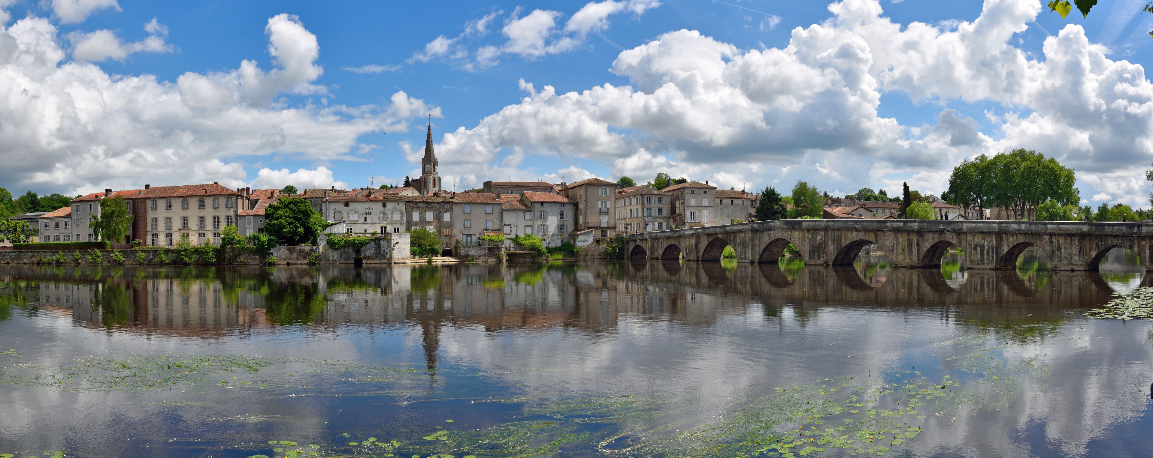 A historic town with a river, a bridge, and a church tower.