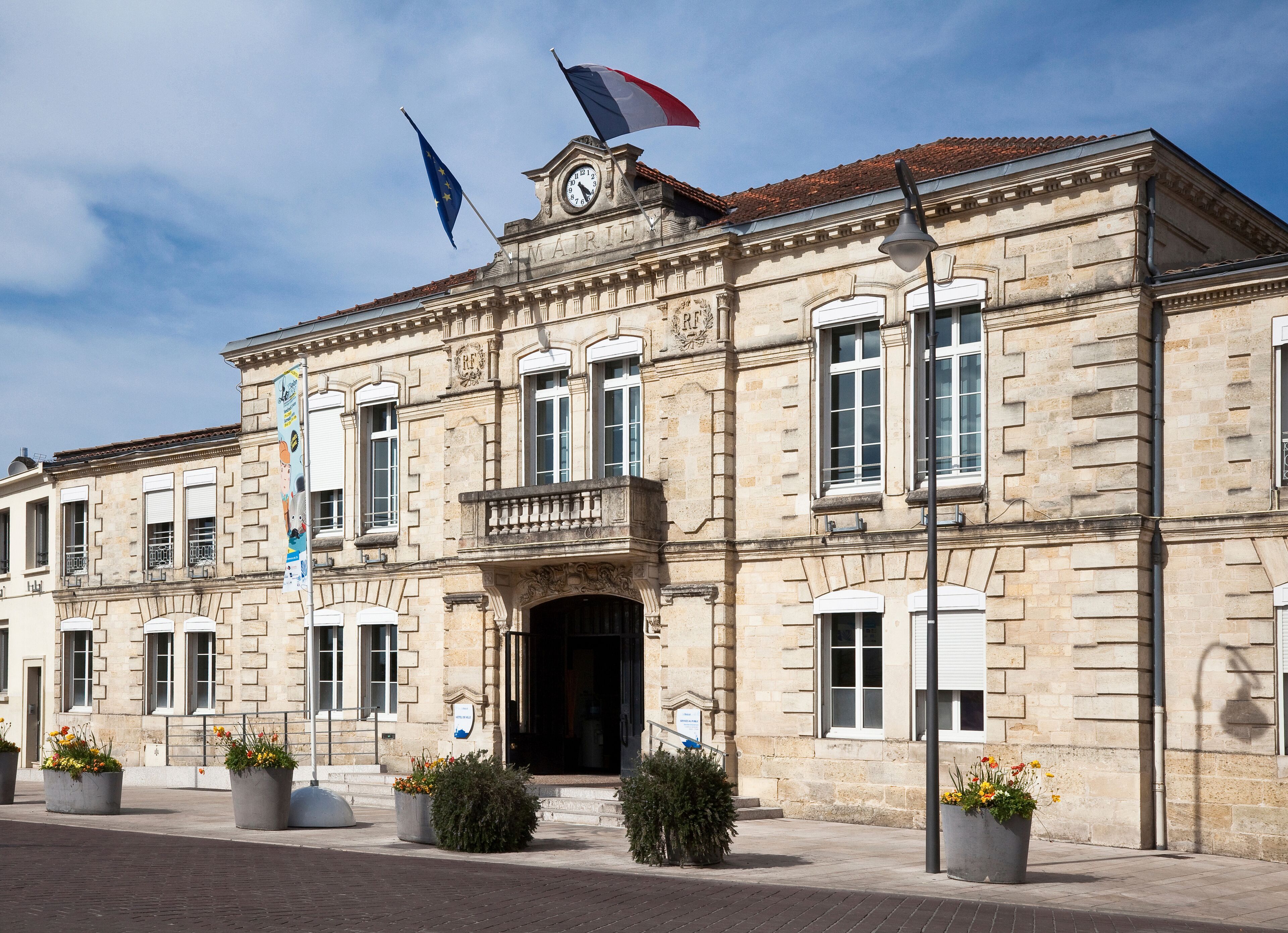 A historic building with a clock tower, flags, and classical architecture.