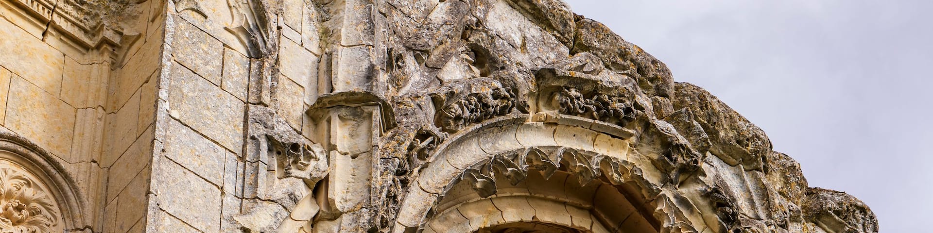 A weathered stone archway with intricate carvings and a circular window.