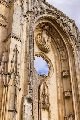 Un arco de piedra erosionado con intrincados grabados y un ventanal circular.
