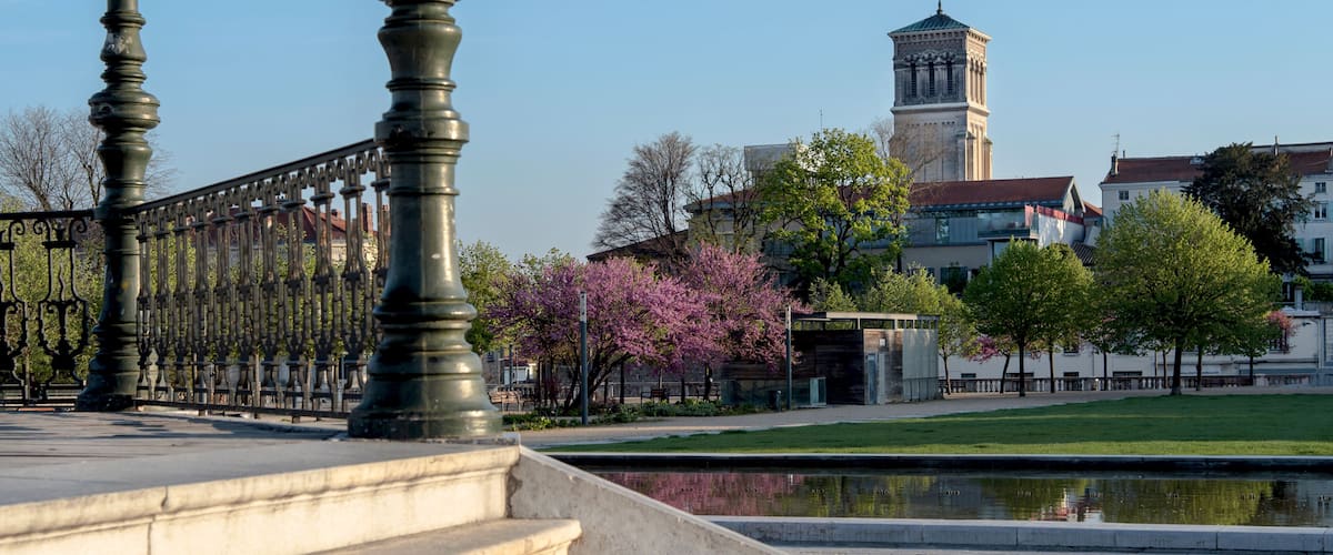 A stone staircase, a metal fence, a pond, and a tower in the background.