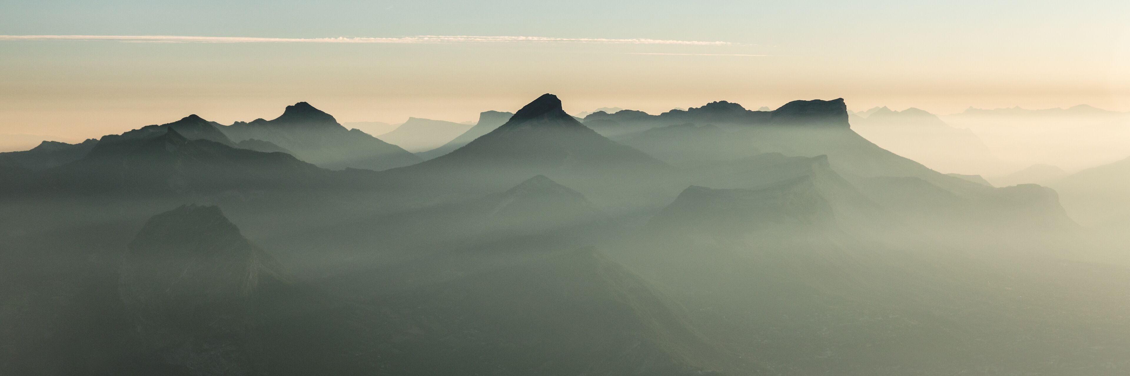 A mountain range with mist-covered peaks and a clear sky.
