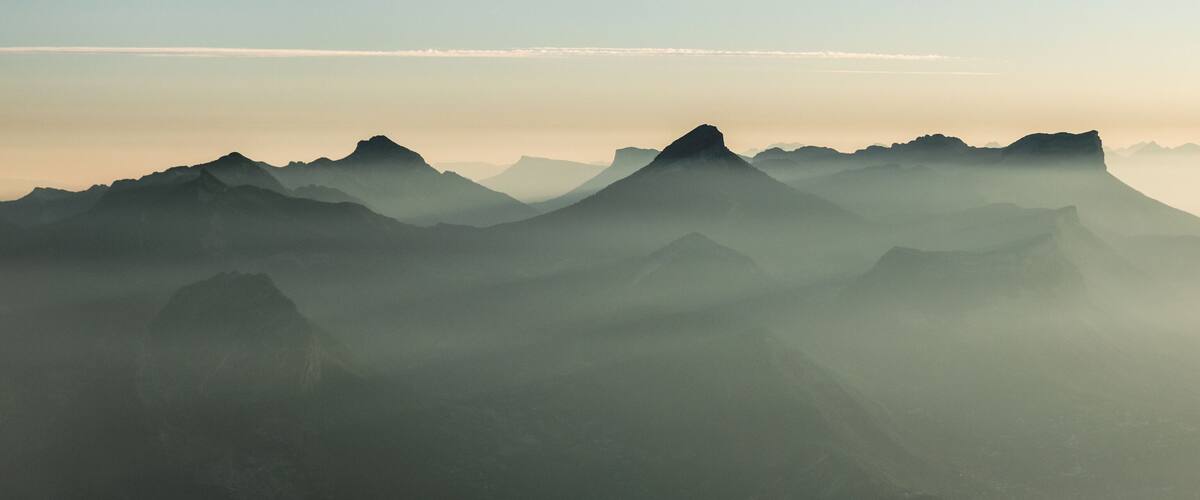 A mountain range with mist-covered peaks and a clear sky.