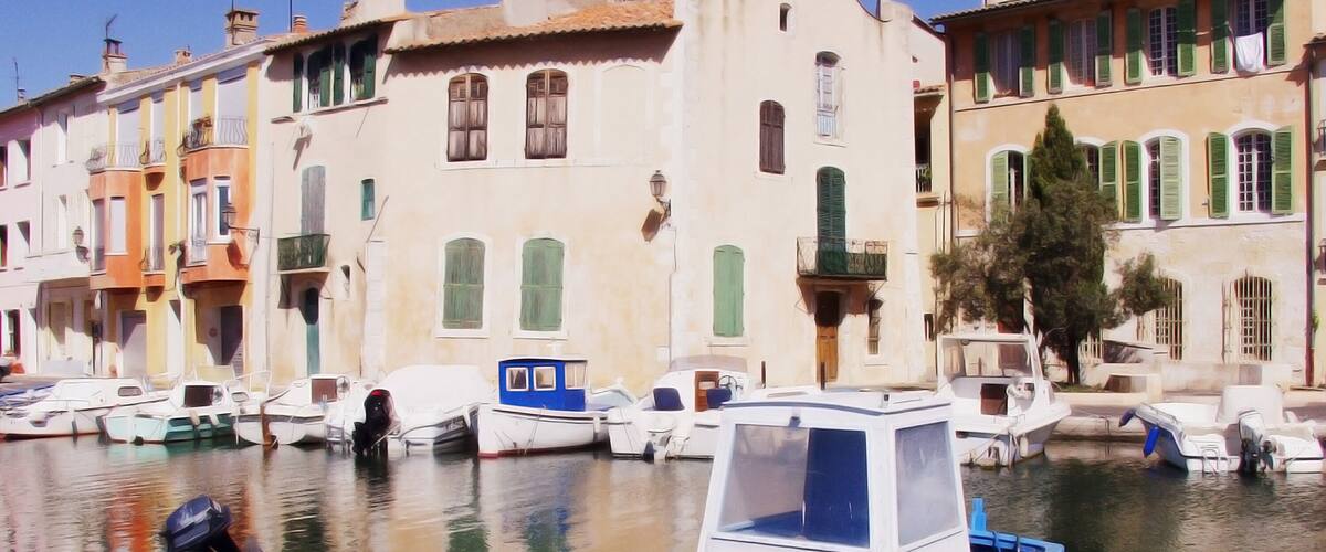 A blue boat docked in a marina with colorful buildings in the background.
