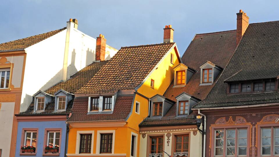 A row of colorful buildings with distinct architectural styles and a clear blue sky.