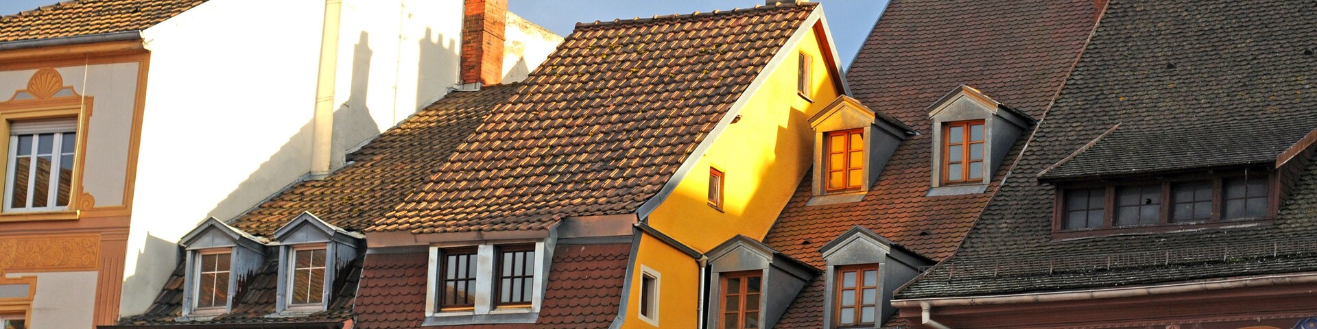 Una hilera de edificios coloridos con estilos arquitectónicos diferentes y un cielo azul despejado.