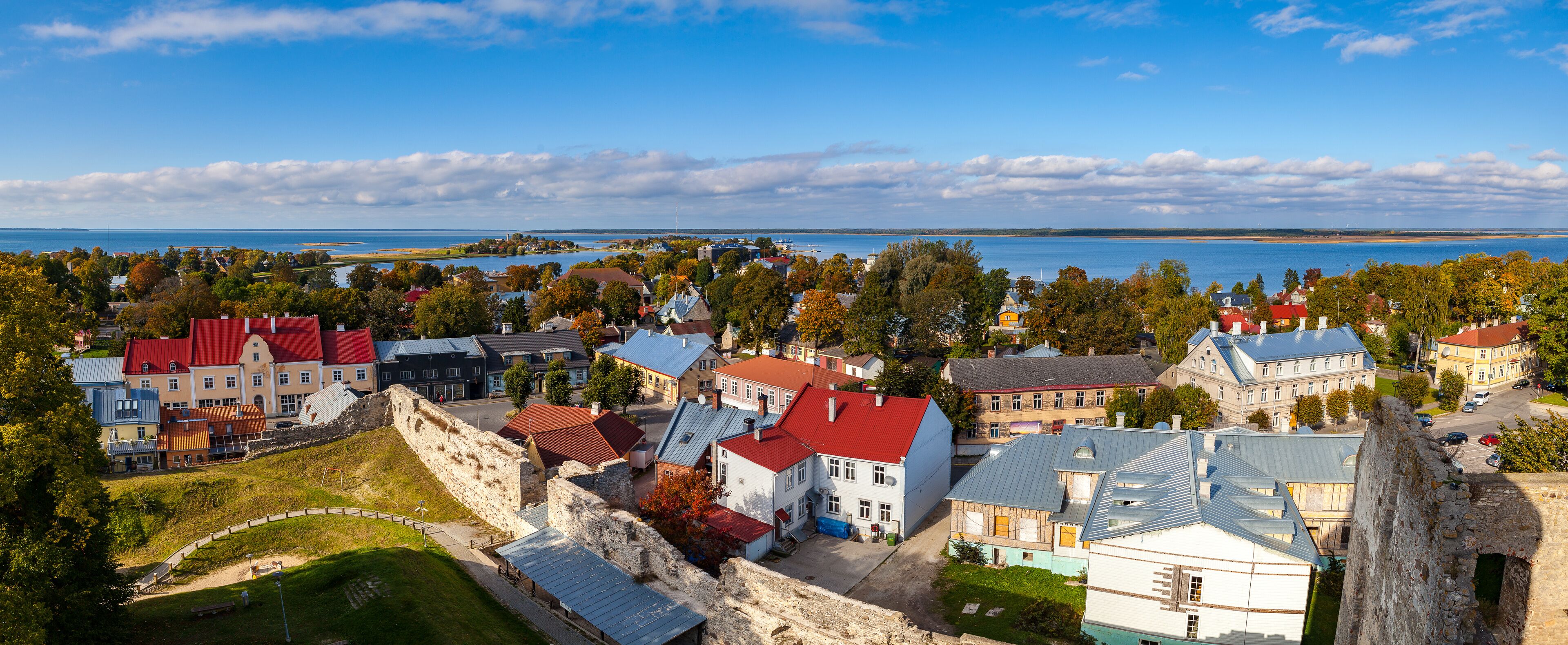 A coastal town with historic buildings, a large body of water, and a prominent stone wall.