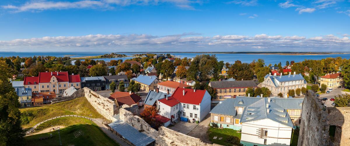 A coastal town with historic buildings, a large body of water, and a prominent stone wall.