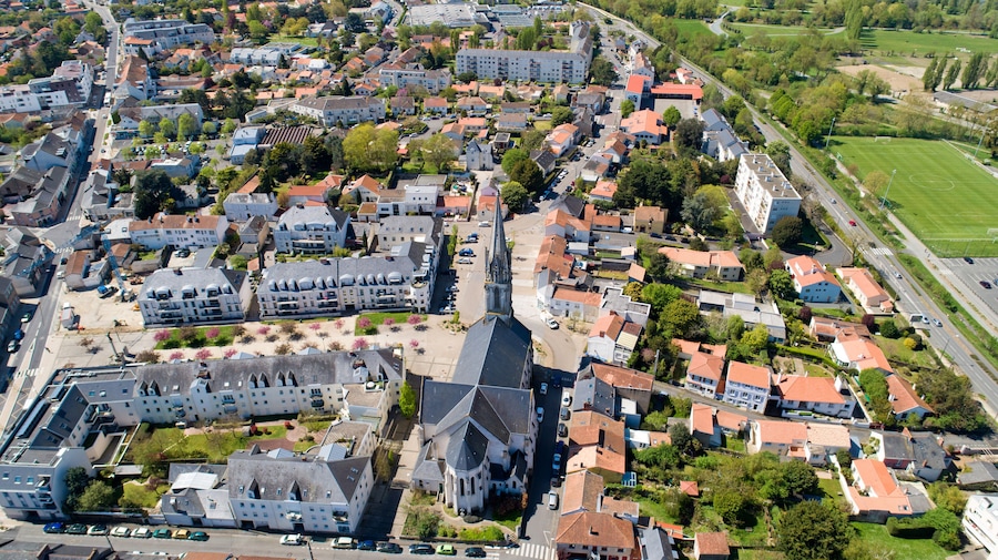 Vista aérea de un pueblo con una iglesia destacada, edificios residenciales y un campo deportivo.